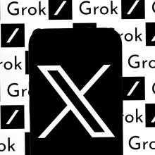 A phone displaying the X logo in front of a screen displaying the Grok logo.