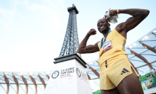 Grant Holloway poses with the gold medal in front of a miniature Eiffel Tower 