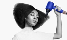 person using blue dyson supersonic hair dryer to style their hair