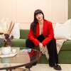 Gigi Engle, a white woman with long dark hair, sits on a green sofa. 