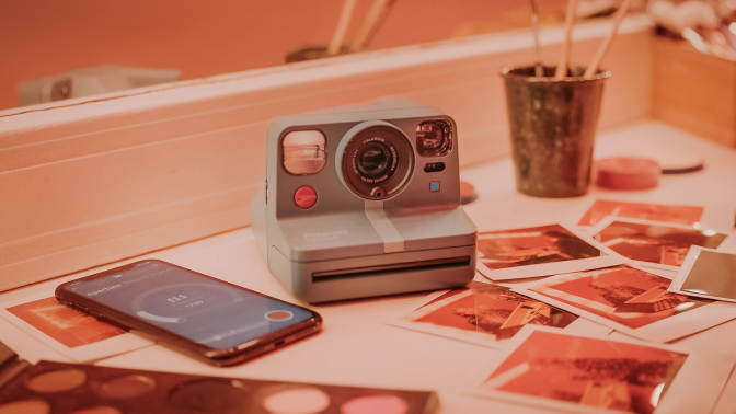 Polaroid camera on countertop surrounded by printed photos