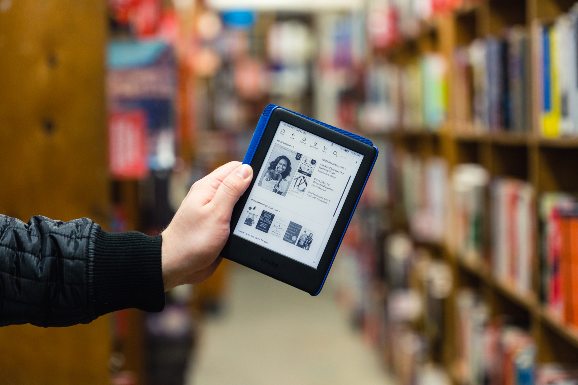 A person holds a Kindle in one hand. 