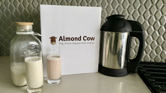 Almond cow nut milk maker next to a jug and two glasses of alternative milk