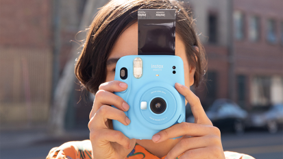 person holding blue fujifilm instax camera