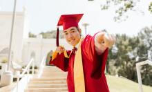 a man in red academic regalia smiling while wearing mortarboard