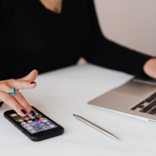 Woman using smartphone while on her laptop 