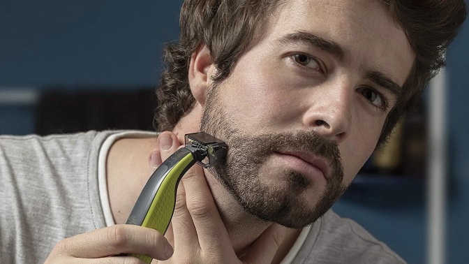 Person using a Philips Norelco OneBlade electric razor to shave.