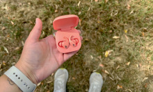 A person holding a pair of Beats Fit Pro against a lawn