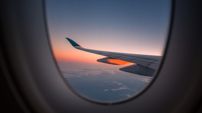 Wing of plane and sunset out window of airplane