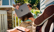 a teenage boy holding up an hp chromebook x360 and putting his legs up while sitting out on a sunny porch