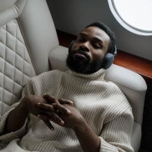 Person lying in airplane chair with headphones on and eyes closed.