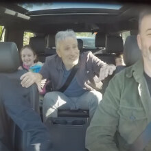 A group of people sit in a car, laughing.