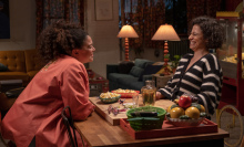 Still from 'Babes' shows Ilana Glazer and Michelle Buteau's characters laughing and sharing snacks.