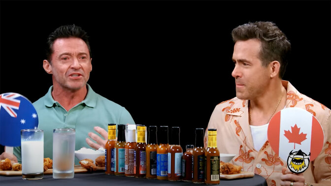 Two men sit at a table covered with hot sauce.