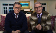 Stephen Colbert and John Oliver sit on a couch