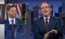 A man in a suit sits behind a talk show desk. In the top-left is an image of another man in a suit.