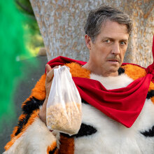 A man in a tiger costume looks angry while holding up a bag of cereal.