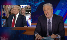 A man in a suit sits behind a talk show desk making a face. In the top left is an image of Donald Trump.