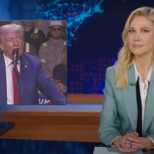 A woman sits at a talk show desk. In the top-left is an image of a man standing at a podium in front of a crowd.