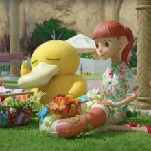 In a stop-motion Pokemon TV series, Psyduck sits with a girl on a green lawn with baskets of flowers.