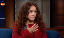 A woman sits in a talk show chair looking at the host, who is off-camera.