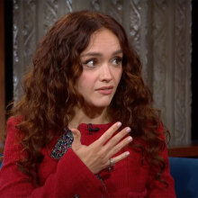 A woman sits in a talk show chair looking at the host, who is off-camera.