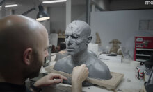 A man stands in front of a grey prosthetic head on a table.