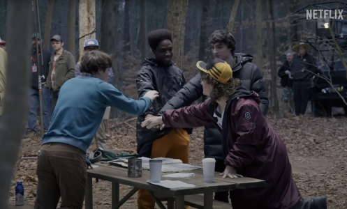 On set for "Stranger Things," four boys put their hands together.