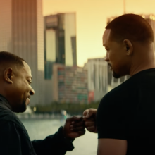 Martin Lawrence and Will Smith bump fists by the water.