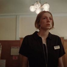 A woman stands in a hotel reception looking afraid.