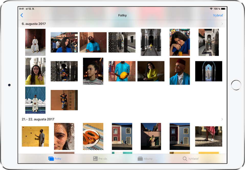 Apka Fotky v zobrazení na šírku. Naspodku obrazovky sú zľava doprava taby Fotky, Pre vás, Albumy a Vyhľadať. Je vybraný tab Fotky a na obrazovke sú zobrazené miniatúry fotiek v mriežke zoskupené podľa momentov. Nad každým momentom je dátum, kedy boli fotky spravené. Klepnutím na dátum zobrazíte podrobnosti momentu. Klepnutím na miniatúru fotky ju zobrazíte na celej obrazovke.