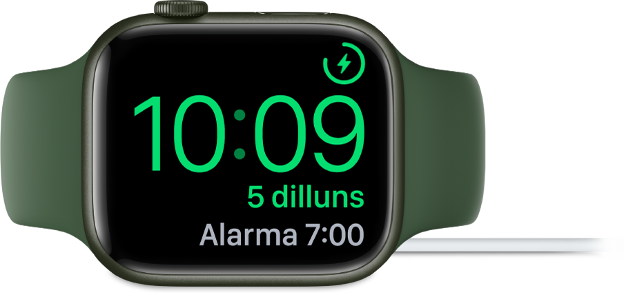 Un Apple Watch posat de costat i connectat al carregador amb la pantalla que mostra el símbol de càrrega a l’angle superior dret, l’hora actual a sota i l’hora de l’alarma següent.