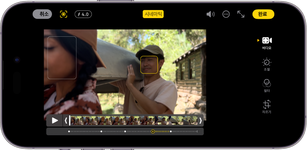 시네마틱 모드 비디오의 편집 화면이 가로 화면 방향으로 표시됨. 화면 왼쪽 상단에 취소 버튼, 시네마틱 사용 설명서 버튼 및 심도 조절 버튼이 있음. 화면 상단 중앙에 시네마틱 버튼이 선택되어 있음. 화면 오른쪽 상단에 음량 버튼, 추가 옵션 버튼, 전체 화면 시작 버튼, 완료 버튼이 있음. 화면 중앙에 비디오가 있고 피사체 초점 주변을 프레임이 둘러싸고 있음. 비디오 아래에는 비디오에서 피사체 초점이 변경되는 지점을 표시하는 프레임 뷰어가 있음. 다음과 같은 편집 버튼은 화면 오른쪽에 위에서부터 아래로 나열되어 있음. 비디오, 색상 조절, 필터, 자르기.