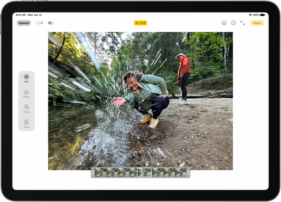 Live Photo ada di bagian tengah layar Edit di app Foto. Penampil bingkai terdapat di bagian bawah video dan garis kuning terdapat di sekitar bingkai yang dipilih untuk disertakan di Live Photo yang diedit; satu bingkai dipilih untuk membuat foto utama. Tombol pengeditan berada di sisi kiri layar, dari atas ke bawah, Live Photo, Sesuaikan, Filter, dan Potong. Live Photo dipilih.