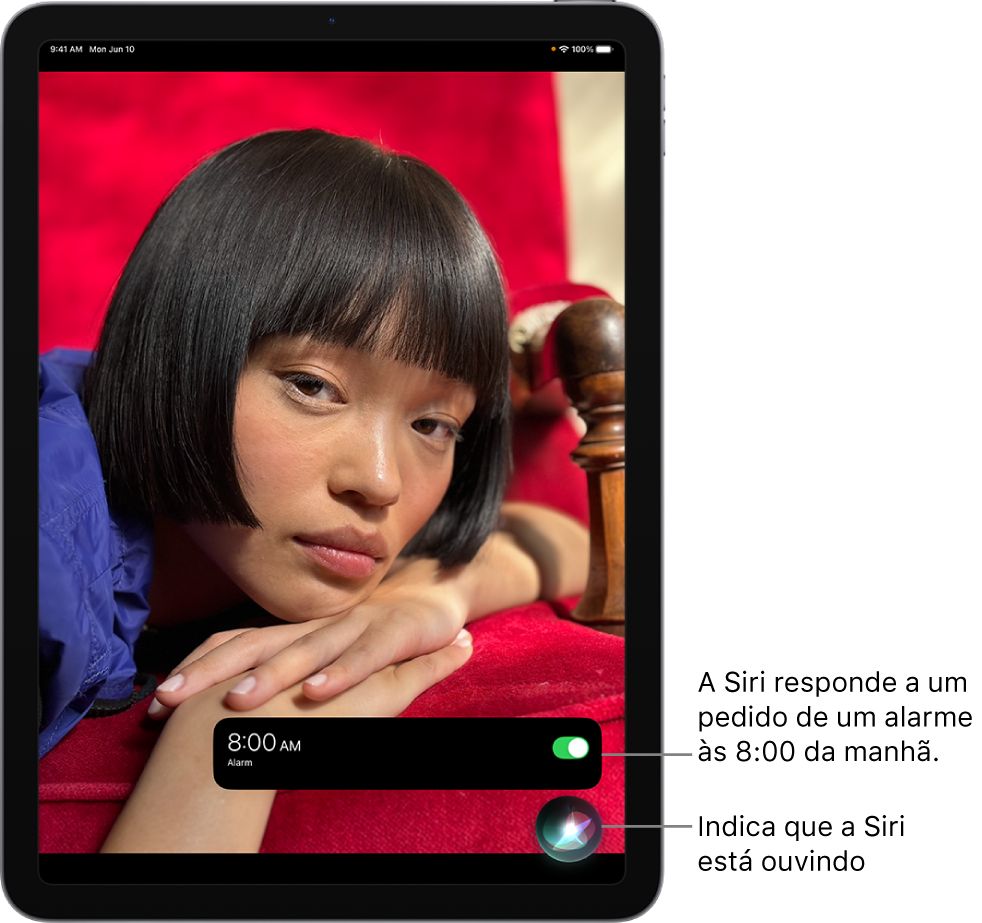A tela de um iPad. Perto da parte inferior da tela, uma notificação do app Relógio mostra que um alarme está ativado para as 8 horas da manhã. Um ícone abaixo da notificação indica que a Siri está ouvindo.