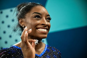 simone biles holds up a necklace of a goat after winning the individual all around competition in the 2024 paris olympics