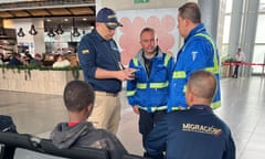 Colombian authorities speak with a young boy at an airport setting.