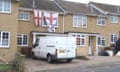 A white van parked in front of a house hung with the St George's flag