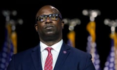 Black man wearing glasses, blue suit and red patterned tie