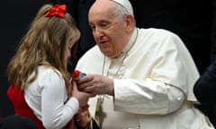 Pope Francis distributes sweets to a small girl with a red ribbon in her hair