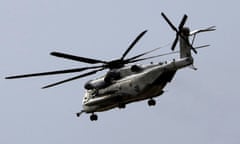 A large, black helicopter with six rotors on top and on four on the tail in the sky.