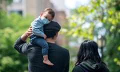 A toddler in a mask sits on his father’s shoulder during a walk through Central Park in New York.