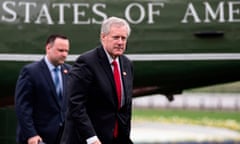 White middle aged man with poofy white hair, dark suit, red tie, in front of dark green airplane with some white letters visible: 'States of Ame'.