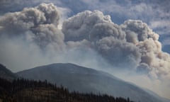 An impressive gray cloud seemingly miles long and high, above a smoky hillside.