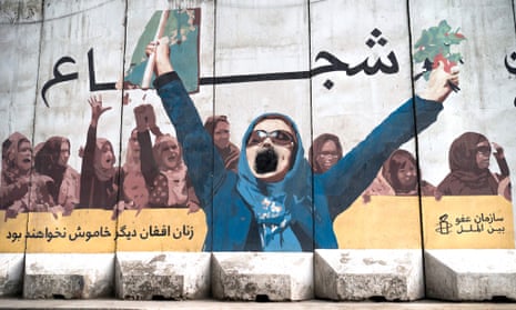 A wall mural on a street in Kabul shows protesting women. The foremost woman has her arms raised, but her open mouth has been spraypainted black. Writing in Arabic reads: 'Afghan women will not be silent anymore'