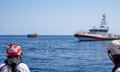 MSF volunteers look on at large Libyan coastguard ship and two smaller vessels