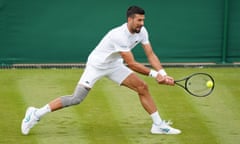 Novak Djokovic reaches for a shot while wearing a knee support during preparation for Wimbledon.