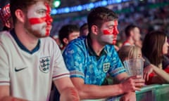 Two young men wearing England football shirts with the St George's cross painted on their faces looking sad