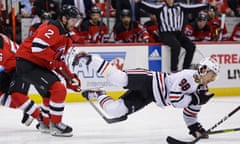 Blackhawks center Connor Bedard falls to the ice after being checked by Devils defenseman Brendan Smith (2) during the first period of Friday’s game in Newark, New Jersey.