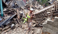 A man retrieves a child’s bicycle from the ruins of damaged properties in West Lombok, Indonesia.